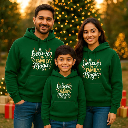 Family of three wearing green hoodies with 'believe in Family Magic' text