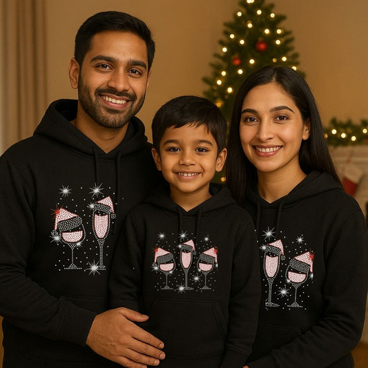 Family of three wearing matching black hoodies with a festive design