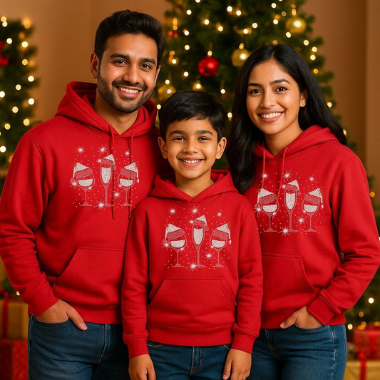 Family of three wearing red hoodies with a Christmas design