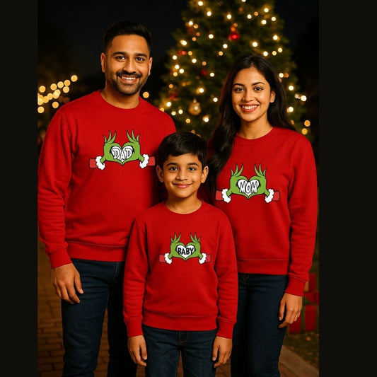 Family of three wearing red sweatshirts with a green graphic