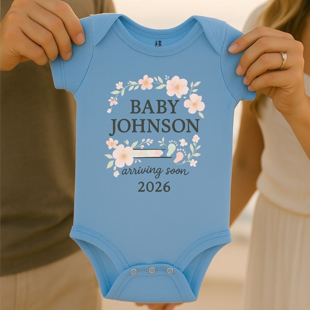 Pastelblue baby onesie with 'Baby Johnson arriving soon 2026' text with floral and baby footprint graphic design