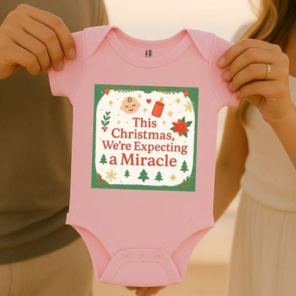 Pink baby onesie with "Thsi Christmas, We're Expecting a Miracle" text and feeding bottle and baby graphic design.