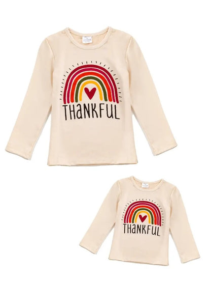 Beige T-shirts for adults and children with a colorful Rainbow graphic image and 'THANKFUL' texton the front.