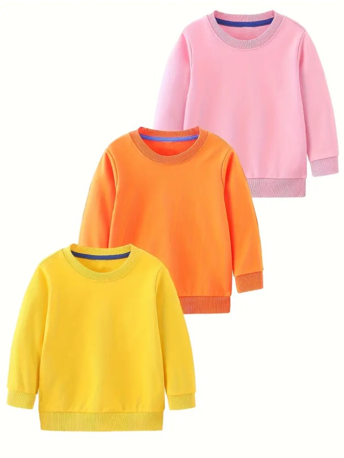 Three toddler-sized sweatshirts in mustard, orange, and light pink colors, laid out flat.