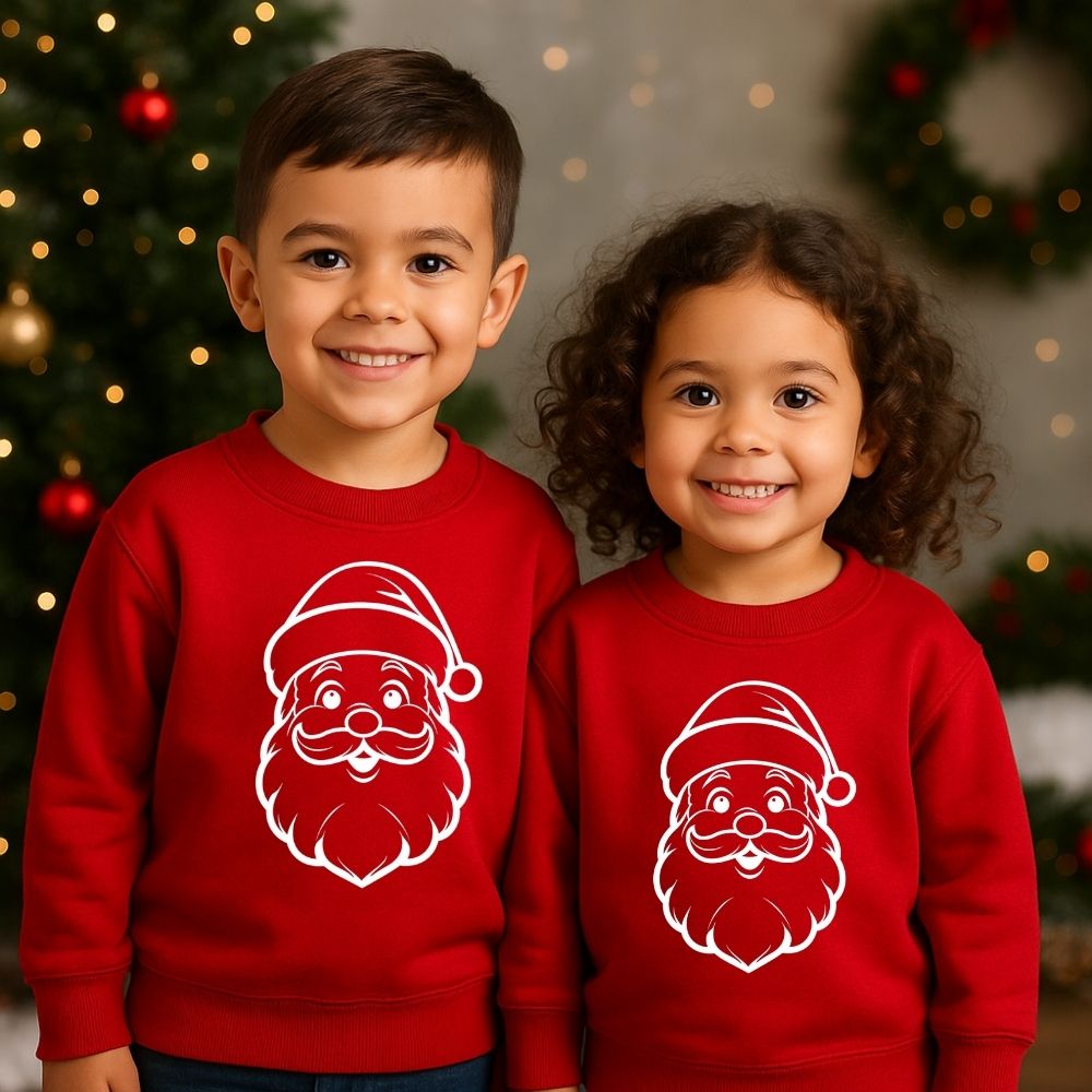 Two children wearing red Christmas sweaters with Santa Claus faces