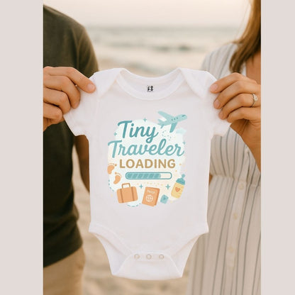 White baby onesie with 'Tiny Traveler Loading' text and travel-themed graphics 